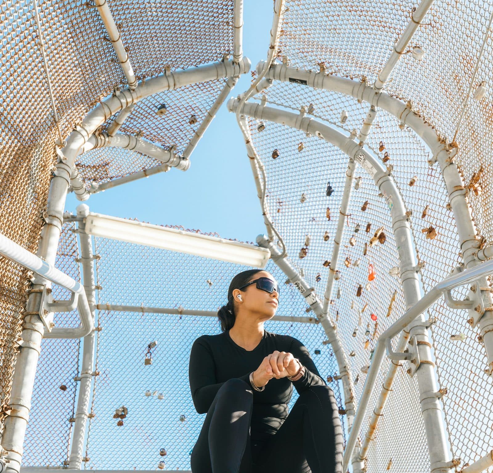 Woman in a black long-sleeve top and leggings sitting on steps