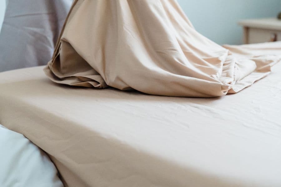 Elasticated fitted sheet being drawn over a mattress corner