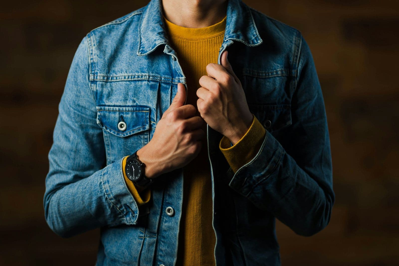 Close-up of a light-wash denim jacket worn over a mustard top