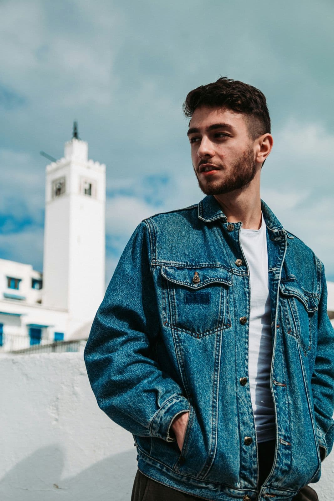 Man wearing a mid-blue denim trucker jacket over a white t-shirt