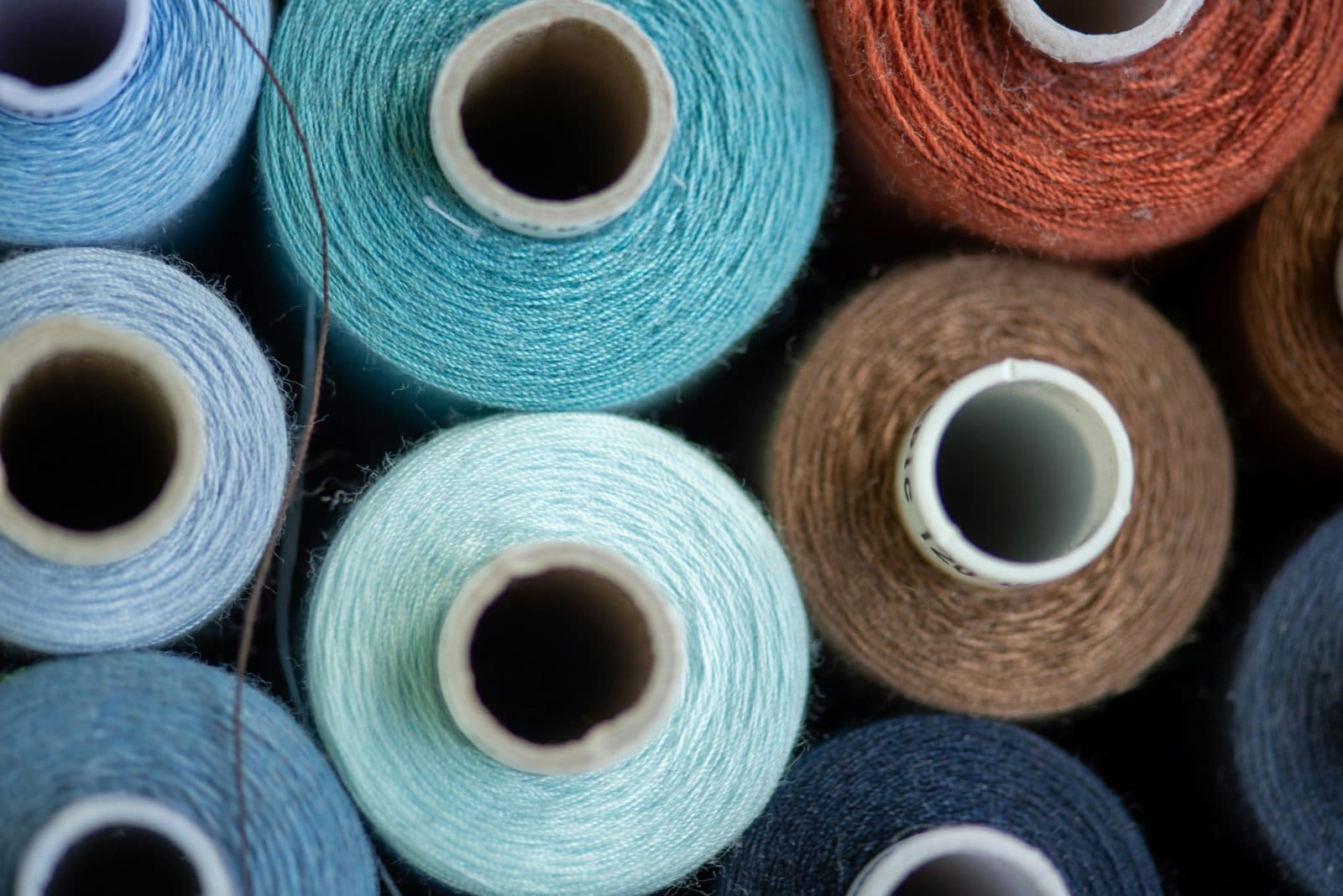 Close-up of coloured sewing thread spools in blue, teal, brown and orange